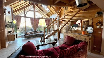 Ein geräumiges Wohnzimmer mit großem Fenster, einer Holztreppe und einer gemütlichen Sitzecke.