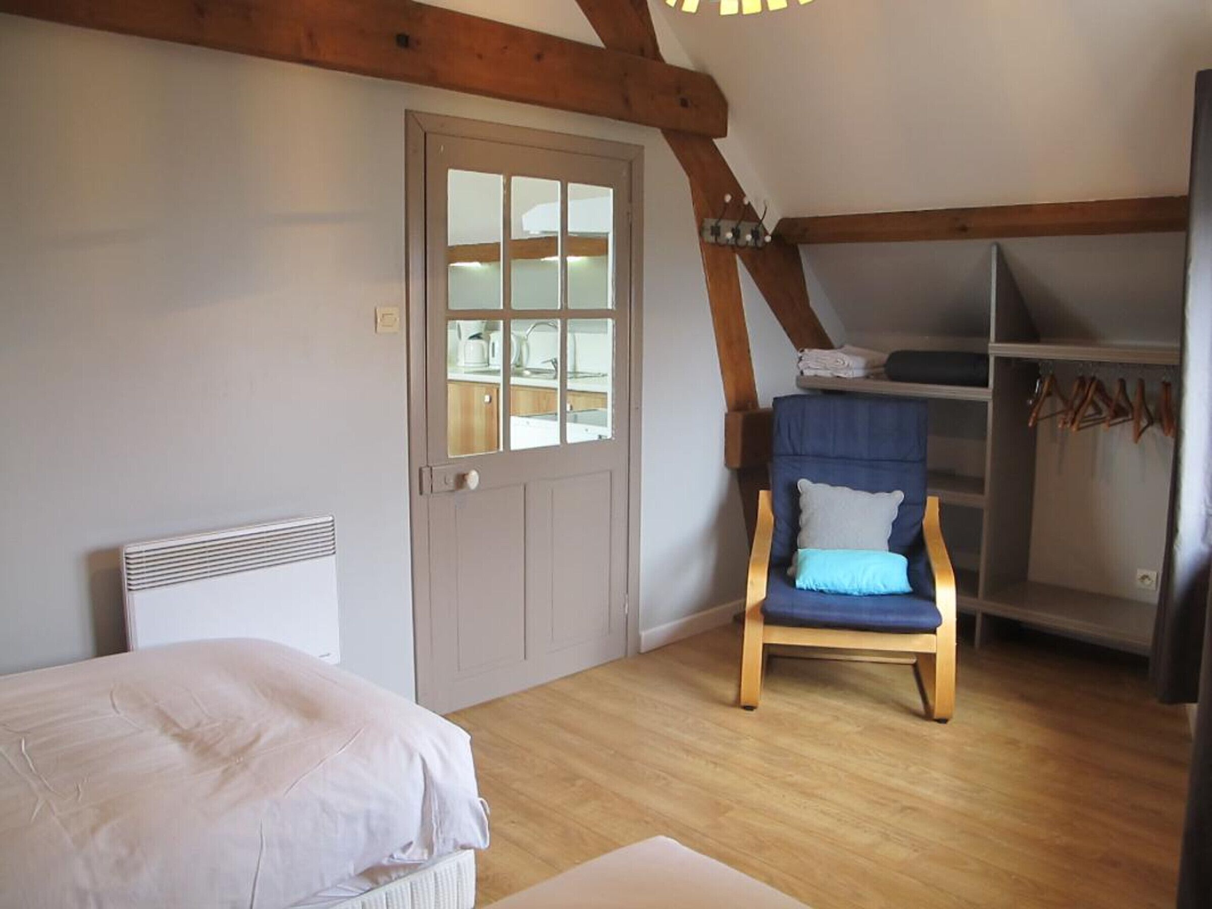Une chambre à coucher avec un lit, une chaise, une armoire et une porte avec une fenêtre.