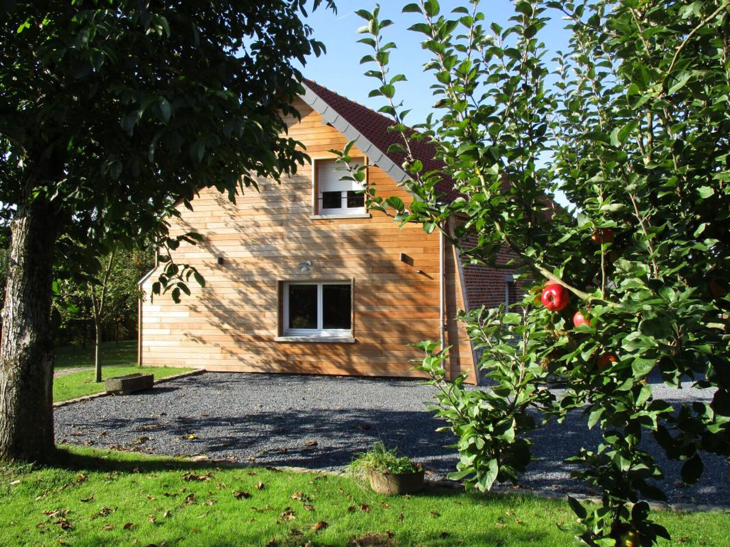 Une maison à deux étages, avec un toit en pente, une petite fenêtre et une allée gravillonnée.
