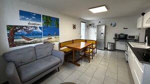 Un espacio habitable compacto con sofá, mesa de comedor y kitchenette.