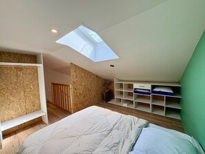 Ein Schlafzimmer mit Oberlicht, Holzverkleidung, einem Bett und Einbauschränken.