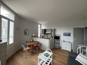 Ein kompakter Wohnbereich mit Essplatz, Küchenzeile und einer kleinen Sitzecke.