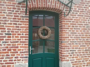 A green door with a glass panel and a woven wreath.