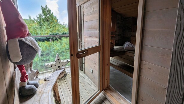 Una cabaña de madera con un ventanal grande, un peluche sobre una roca y una decoración con forma de estrella.