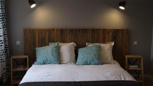 A bedroom with a wooden headboard, two bedside tables, and two wall-mounted lights.