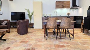 Cozinha moderna com área de jantar, televisão e planta em vaso.