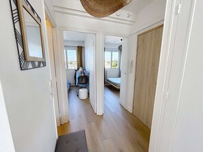 A hallway leading to a bedroom with a bed, a wardrobe, and a window. - Bright apartment in Saint-Paul - 4 guests (Granville)
