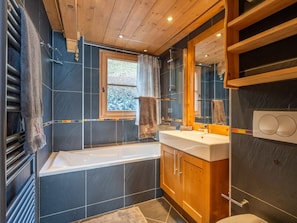 Ein modernes Badezimmer mit Badewanne, einem großen Spiegel und einem hölzernen Waschtisch.