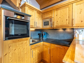 Eine Küche mit Holzausstattung, einem Siemens-Backofen, einer Mikrowelle und einer Kaffeemaschine.