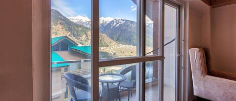 A room with a sliding glass door leading to a balcony with wicker chairs and a table.