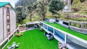 Un patio exterior moderno con piscina, zonas de estar y vistas a un paisaje montañoso.