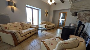 A living room with a sofa, armchairs, a coffee table, and a fireplace.