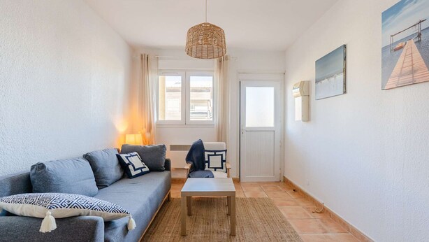 Ein Wohnzimmer mit einer Couch, einem Couchtisch, einer Pendelleuchte und einer Tür zu einem anderen Raum.