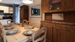 A dining area with a wooden table set for four, surrounded by wooden chairs.