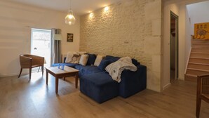A living room with a blue sofa, wooden coffee table, and a stone wall.