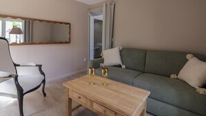 A living room with a wooden coffee table, a green sofa, a black armchair, and a mirror on the wall. - Single-storey house, pets welcome - 4 guests (Silly-en-Gouffern)