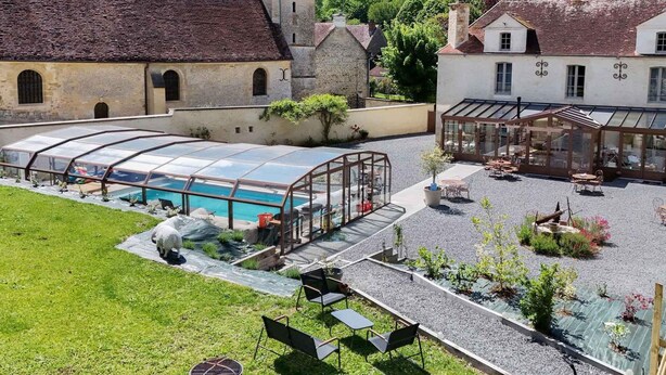 A courtyard with a swimming pool, outdoor seating, and a church. - Single-storey house, pets welcome - 4 guests (Silly-en-Gouffern)
