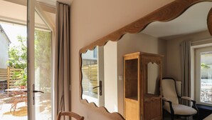 A room with a large mirror, a wooden cabinet, a chair, and a table. - Single-storey house, pets welcome - 4 guests (Silly-en-Gouffern)