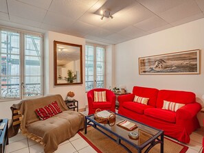 Ein Wohnzimmer mit einem roten Sofa, einem braunen Sofa, einem Glastisch und einem großen Spiegel.