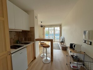 Eine kleine Küche mit einem Kühlschrank, einem Spülbecken und einem Essbereich mit Hockern.