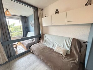 A bedroom with a bed, a window with curtains, a balcony, and a white wardrobe. - Studio with garden view - 4 guests (Cap d'Agde)