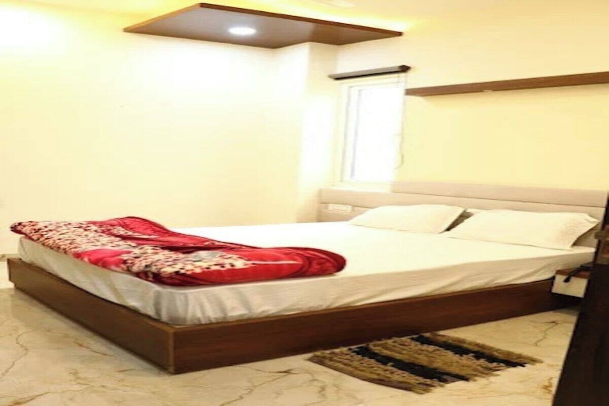 A bedroom with a bed, a headboard, a window, and a ceiling light fixture.