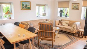 A cozy living room with a wooden dining table, striped sofas, and a patterned rug. - 4 Star Holiday Home in Samso (Samsø)