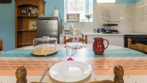 Une table à manger dressée avec des assiettes, un pichet et un verre, dans une cuisine équipée d’un réfrigérateur, d’un four à micro-ondes et d’une cuisinière.