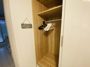 Ein Holzschrank mit Kleiderstange und einem Schild an der Wand.