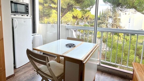 Un balcon donnant sur des arbres, avec une table blanche et des chaises.