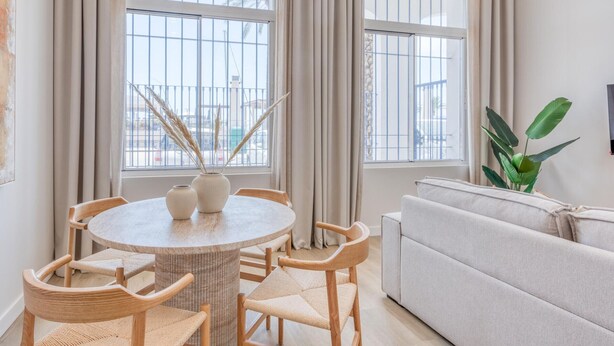 A room with a round table, four chairs, a sofa, and large windows with curtains. - Modern studio, port view - 2 guests (Estepona)