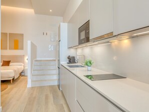 A modern kitchen with a built-in oven, a coffee machine, and a small plant on the counter. - Modern studio, port view - 2 guests (Estepona)
