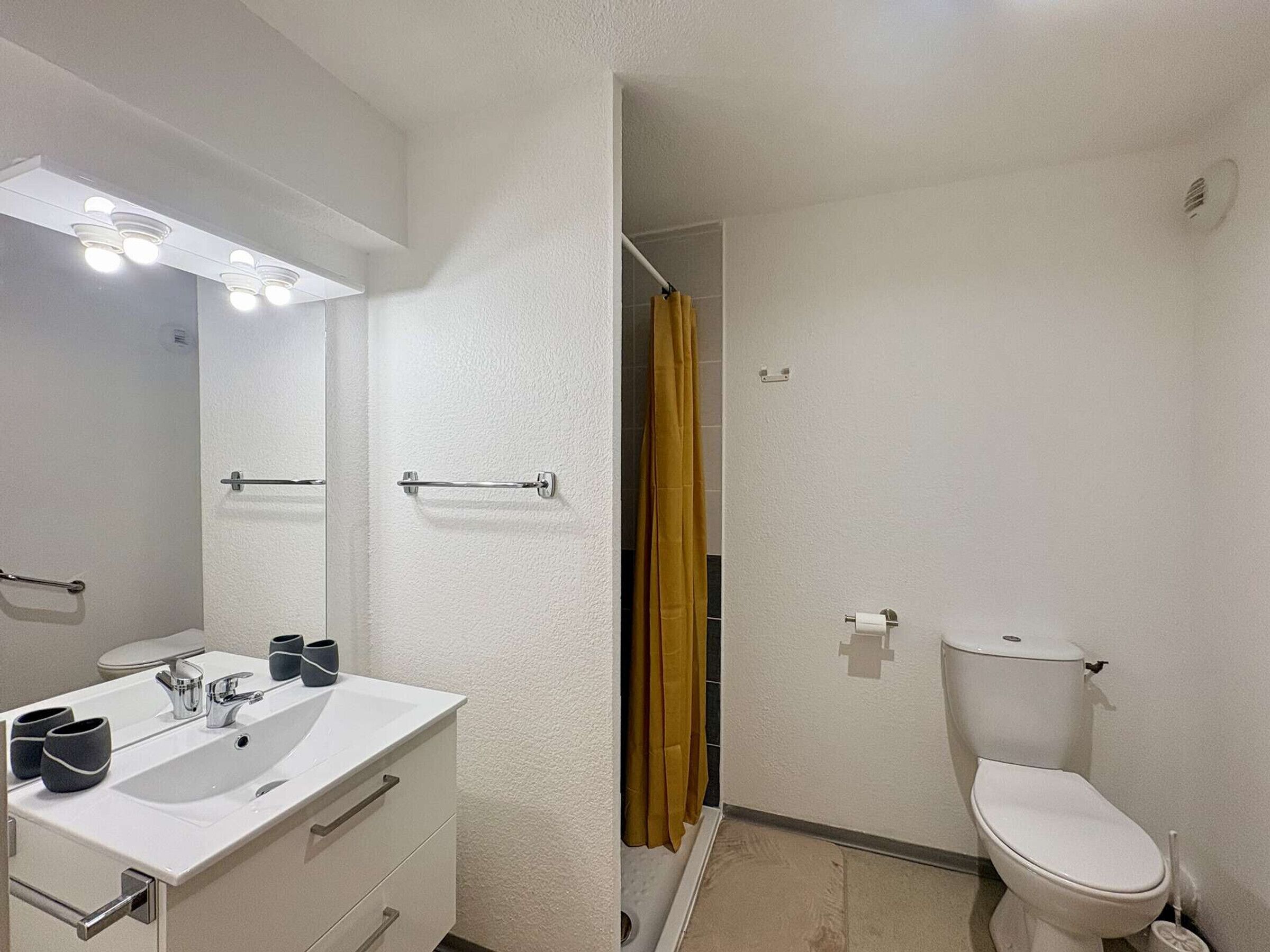 Een badkamer met een wit wastafel, spiegel en toilet.