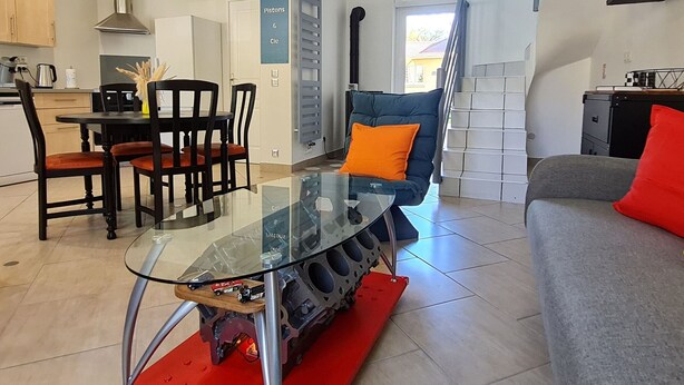 A modern living space with a glass table, a blue sofa, and a grey couch. - Unique house for car enthusiasts (Chenicourt)