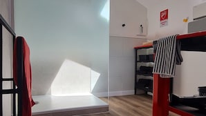 A hotel room with a shower, a red and black bunk bed, a small shelf with toiletries, and a 'PARKING ONLY' sign on the wall. - Unique house for car enthusiasts (Chenicourt)