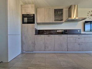 Eine moderne Küche mit grauen Schränken, einer Edelstahl-Dunstesse und einem eingebauten Backofen.