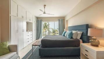 A bedroom with a bed, a nightstand, a desk, a chair, a wardrobe, and a ceiling fan.