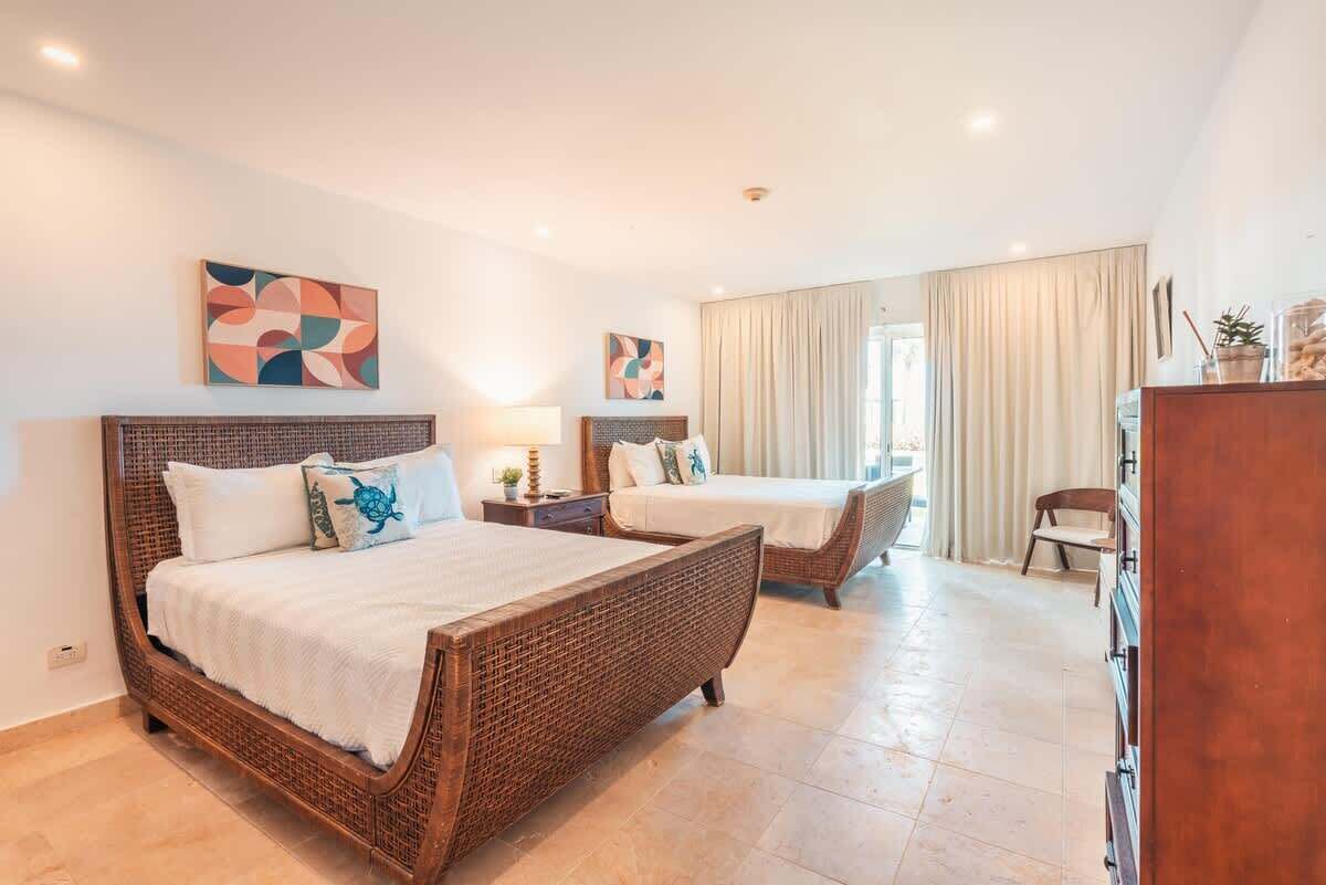 A hotel room with two beds, a wooden headboard, a desk, and a chair.