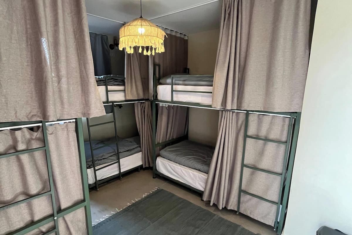 Une chambre de dortoir avec des lits superposés, un luminaire suspendu et un petit tapis.