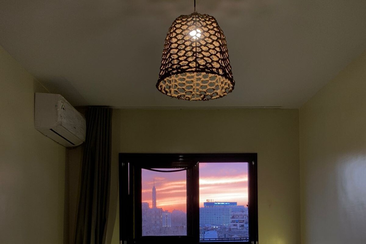 Hotelkamer met een bed, een raam met uitzicht op de stad, een hanglamp en een airconditioning.