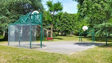 Un parque infantil con un aro de baloncesto y una estructura de escalada con red.