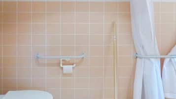 Een badkamer met toilet, een handgreep en een douchegordijn.