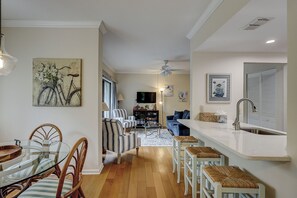 Ein Wohnzimmer mit Essbereich, eine Küche inklusive Spüle und ein Deckenventilator.