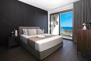 Ein modernes Hotelzimmer mit einem großen Bett, einem Nachttisch mit einer Vase und Blick aufs Meer.