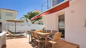 A patio with a dining table, chairs, and a poolside area. - Villa Amarilia - 100m from Pernera Beach (Pernera)