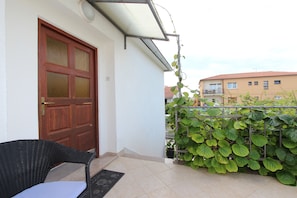 Un balcon avec une porte, une chaise et des plantes en pot.