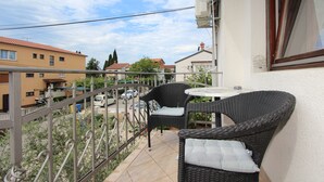 A balcony with wicker furniture, a view of the street, and neighboring buildings. - Rooms and Studio Salvi (Rovinj)