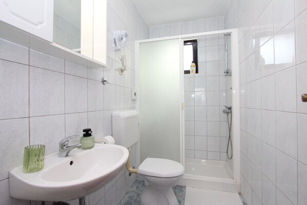 A bathroom with a sink, toilet, and shower.