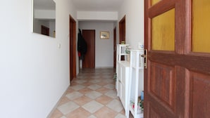 A hallway with a checkered floor, wooden doors, a white cabinet, and a mirror on the wall. - Rooms and Studio Salvi (Rovinj)