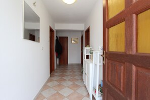 Un pasillo con piso a cuadros, puertas de madera, un armario blanco y un espejo en la pared.